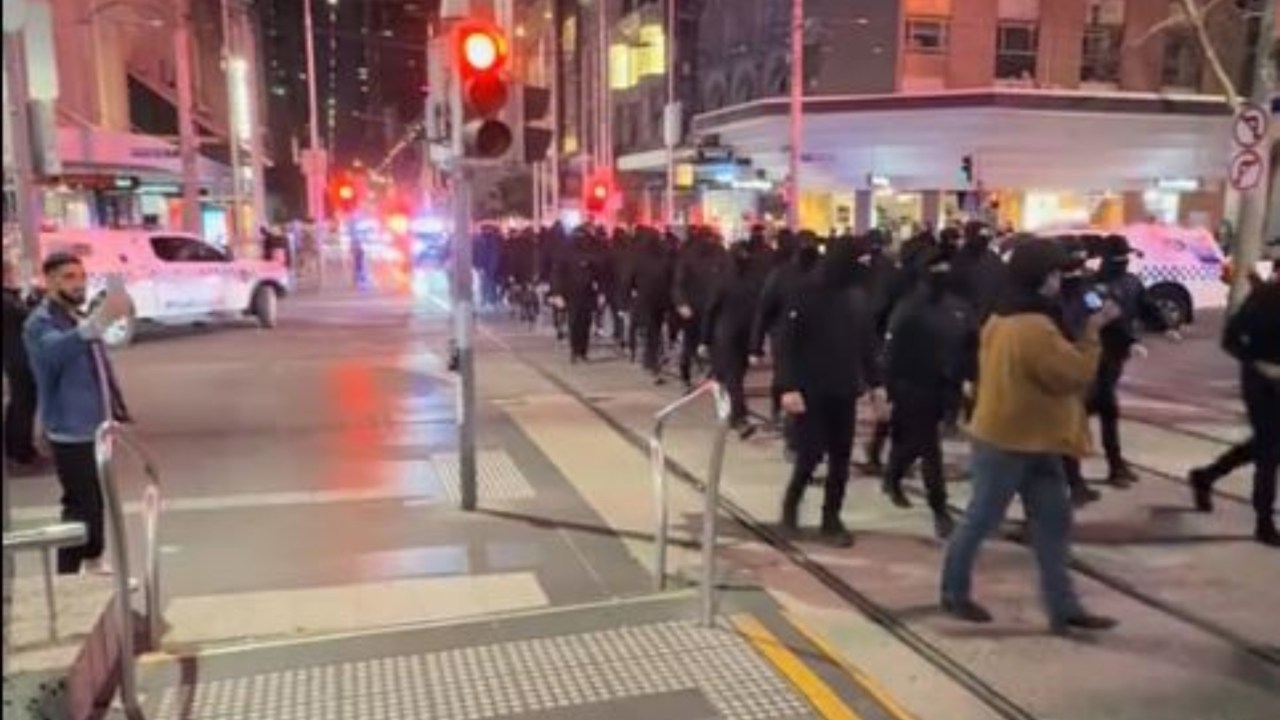 Police investigate assault as dozens of masked men linked to neo-Nazi group parade through Melbourne in midnight demonstration
