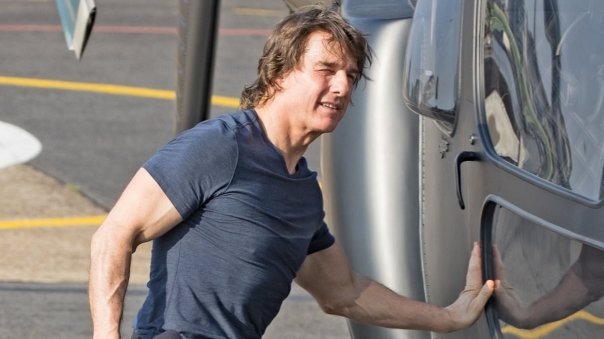 Tom Cruise shows off his 'top guns' in a tight navy T-Shirt as he lands his helicopter following a visit to Pinewood Studios - ahead of the release of his latest Mission: Impossible film