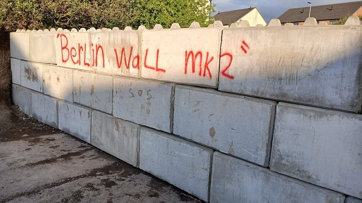 Town at war over 'Berlin Wall MK2' built to block access to a walking route after Google Maps blunder... as furious local knocks it down with a JCB