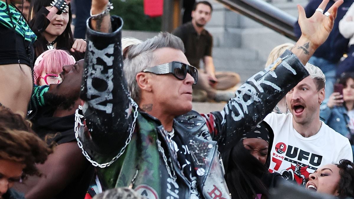 Robbie Williams, 51, rocks a biker jacket as he films dramatic scenes for his latest music video in London