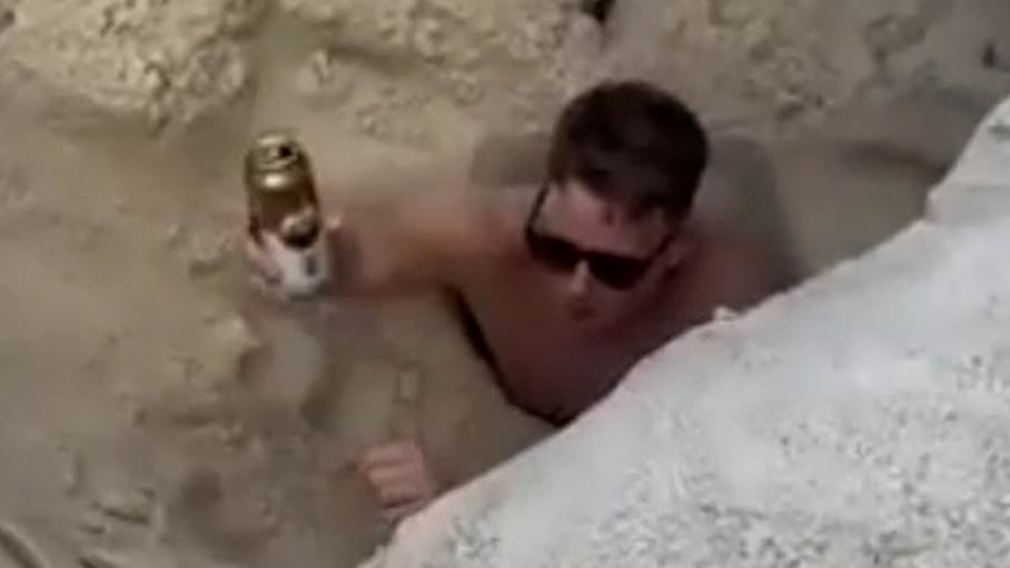 Moment British tourist drinks a beer as he's swallowed by quicksand in hole he had dug on beach in Brazil - before locals and lifeguards spent THREE hours trying to free him
