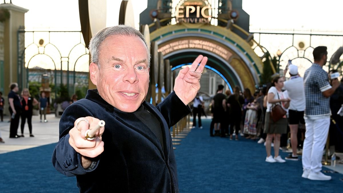 Warwick Davis strikes fun pose with a wand as he celebrates the opening of Universal Epic Universe in Orlando