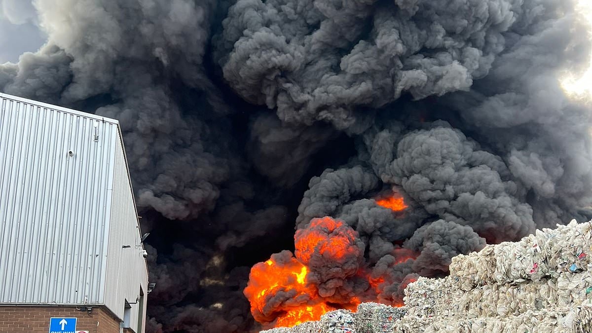 Firefighters rush to massive warehouse blaze as enormous plume of smoke is seen 10 miles away and businesses are evacuated while tons of plastic waste burn