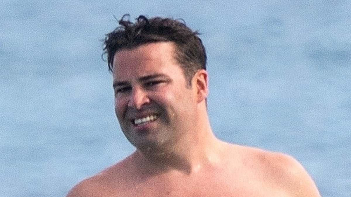 X Factor winner Joe McElderry looks unrecognisable as he shows off his shirtless physique while hitting the beach in Barbados