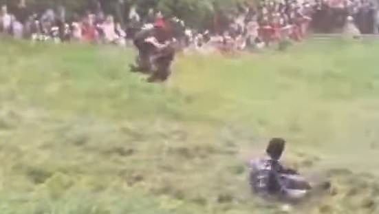 Moment daredevil somersaults down cheese-rolling hill - as organisers call in RUGBY PLAYERS to stop flying participants after council banned tradition over safety fears