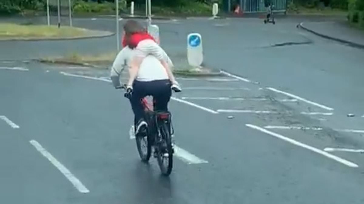 Shocking moment man cycles with child on his back merely gripping his neck - before biking the WRONG way through roundabout