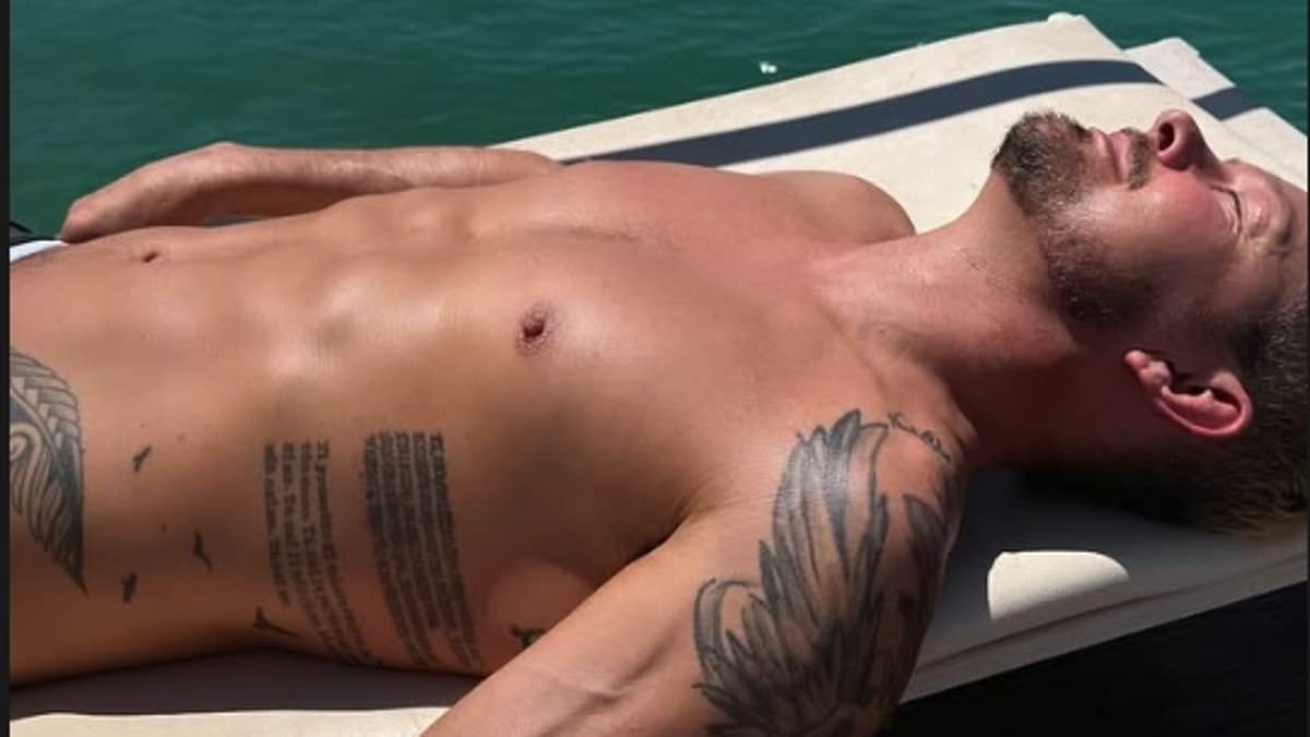 Shirtless Adam Rickitt, 47, show off his buff physique while sunbathing with bikini clad wife Katy before downing a bottle of champagne as the couple celebrate buying a home in Sicily