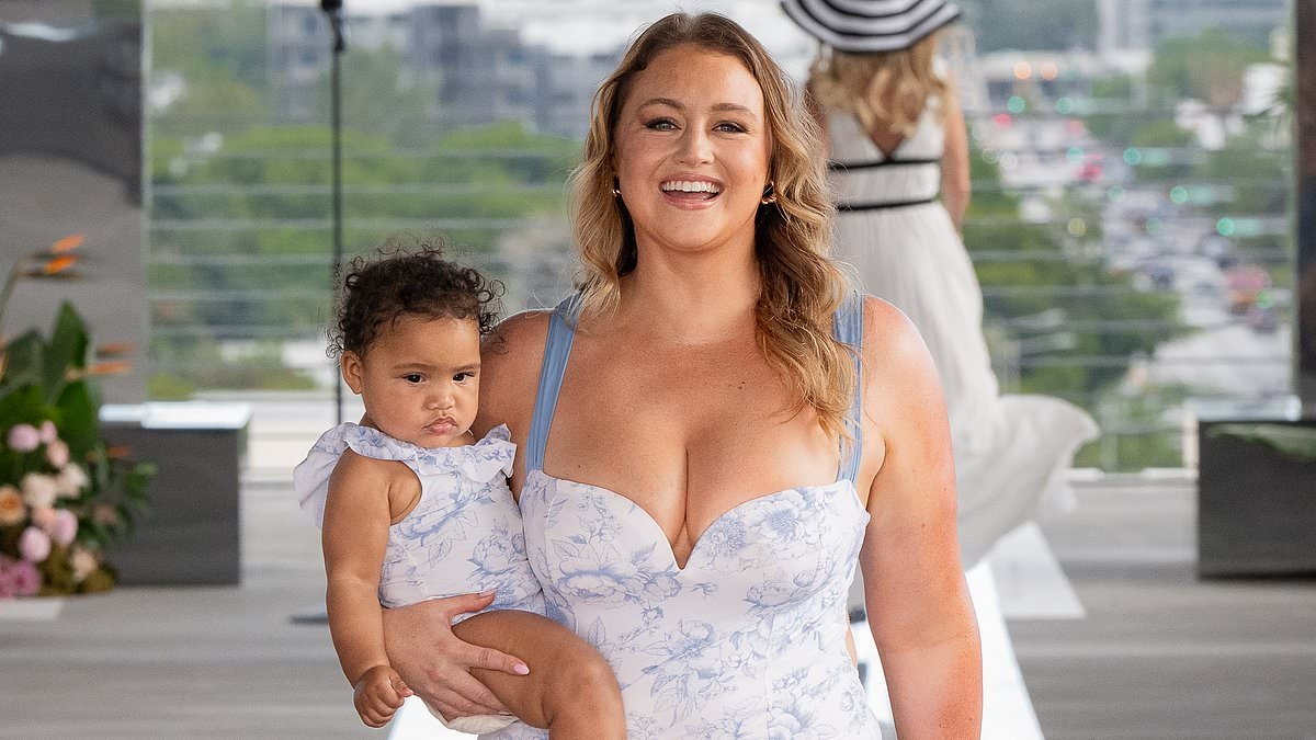 Iskra Lawrence shows off her figure in a blue Cupshe swimsuit as she struts the runway at Miami Swim Week with her baby daughter Prima