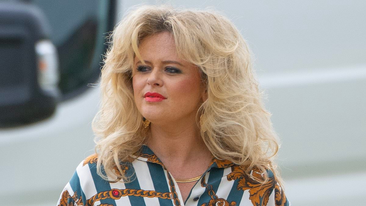 Emily Atack sports voluminous 80's hair and flashes her pins in a navy pencil skirt as she joins Danny Dyer on the set of Rivals series two