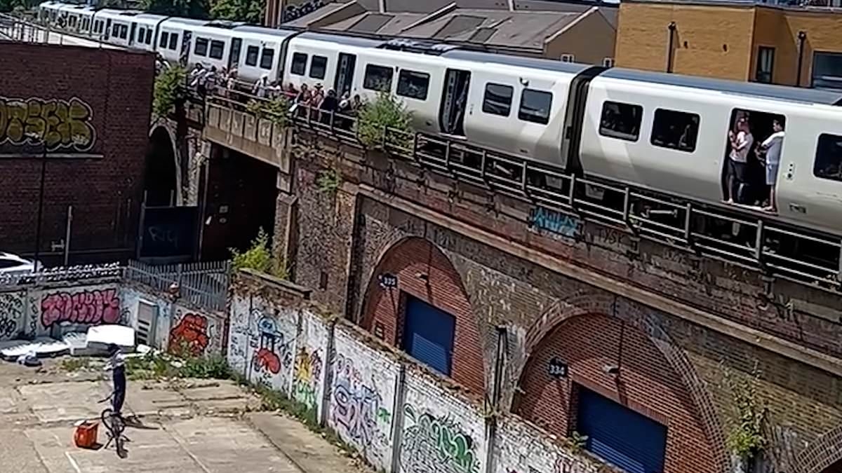 Moment Just Eat rider throws food delivery onto train on track above after it was stranded in sweltering heat