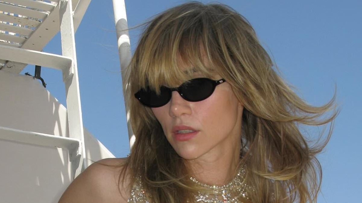 Suki Waterhouse flashes her abs in a dazzling crystal chain top and red shorts as she shares racy snaps