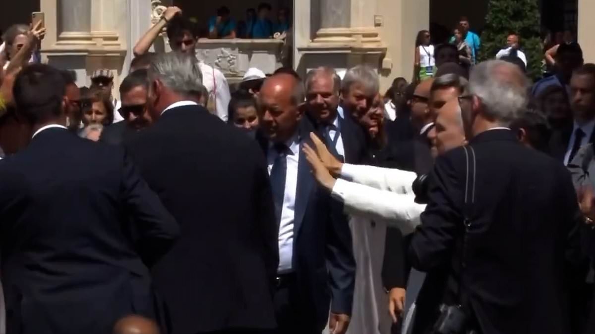 Moment Pope Leo is hit on the head with a flag thrown from worshipers who then charge towards him as he begs them to stay calm in the Vatican