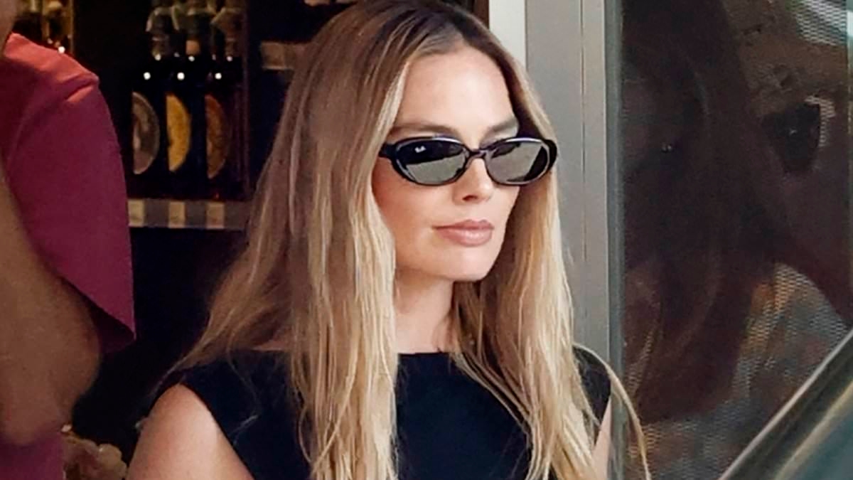 Margot Robbie carries a $1,090 beach bag and looks glamorous in a sheer black dress as she celebrates her 35th birthday in party town Ibiza