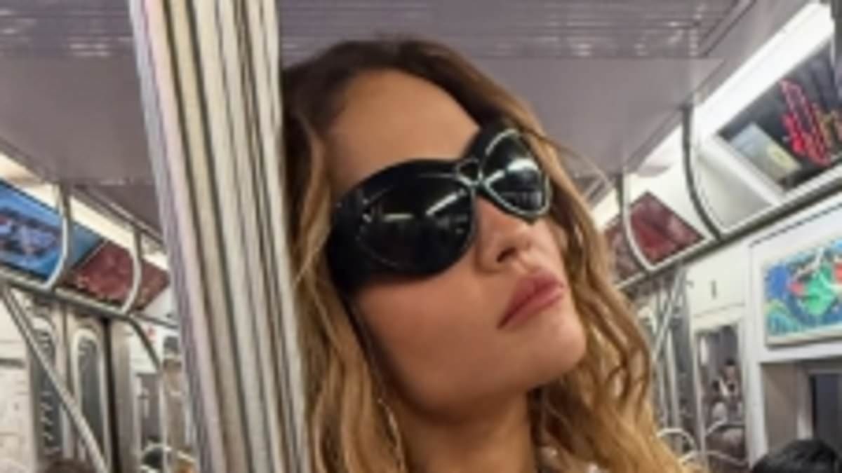 Rita Ora showcases her toned midriff in a skimpy white top as she travels on the subway while exploring Brooklyn