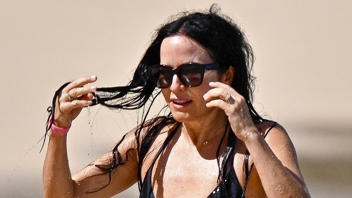 Andrea Corr, 51, showcases her incredibly toned physique in a skimpy black two-piece bikini as she enjoys a stroll along the beach in Barbados