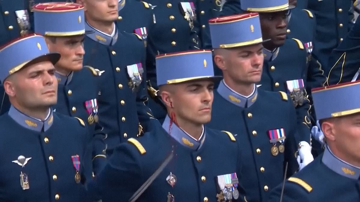 Moment bleeding soldier puts on a brave face during French Bastille Day celebrations as he continues marching with sword in hand