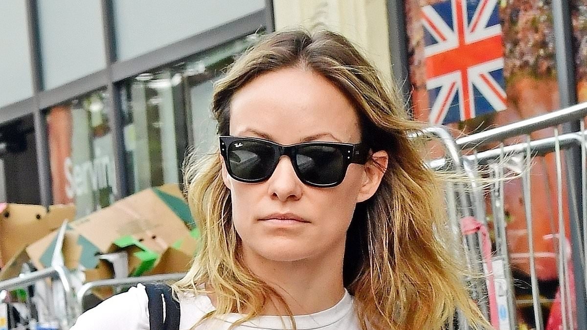 Olivia Wilde cuts a trendy figure in a white love heart T-shirt and flared trousers as she goes shopping in London