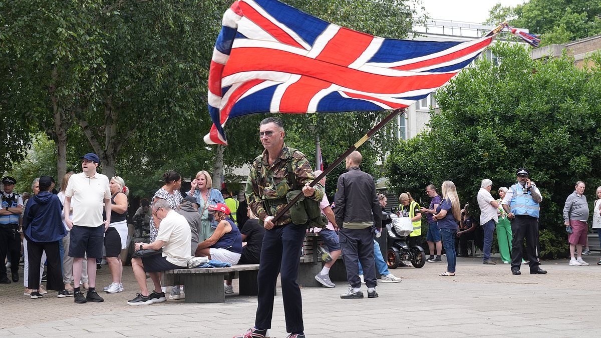 Migrant hotel residents film and laugh as they watch protesters and counter-demonstrators clash on streets of Islington