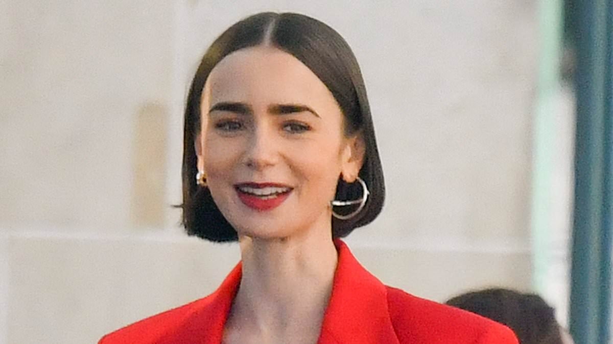 Lily Collins catches the eye in a plunging red suit while carrying her passport as she continues filming for Emily in Paris