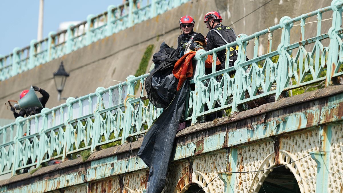 Moment more than a dozen council officers abseiled down wall to clear man's homeless camp on Brighton's seafront