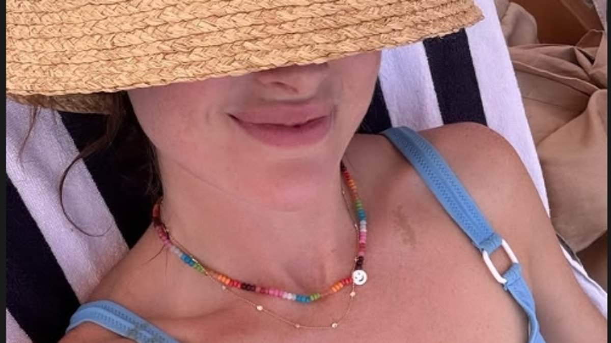Binky Felstead flaunts her washboard abs in a blue bikini top and beige shorts as she heads to the beach during her family summer holiday to France