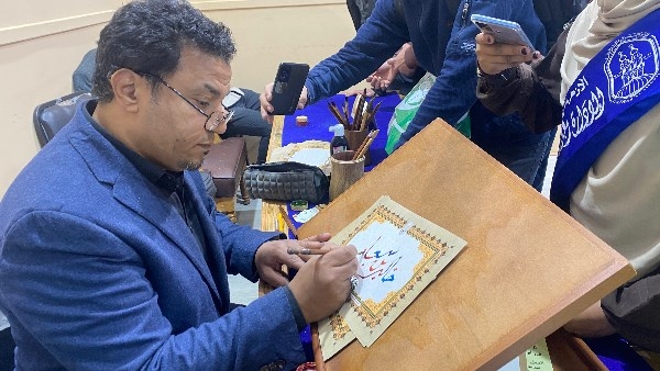 إبداع بالحروف.. فنان يُبهر زوار جناح الأزهر برسم الخط العربي مجانًا