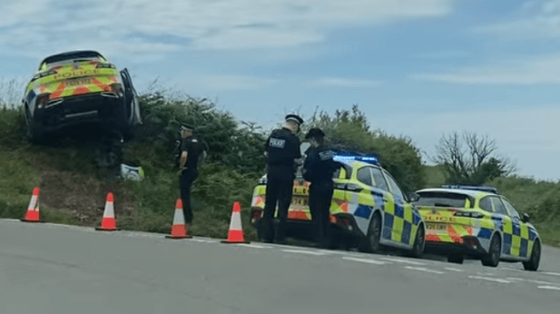 Police car wedged on hedge after leaving road