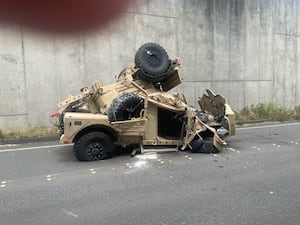 Military vehicle goes over wall on I-90 onto roadway below