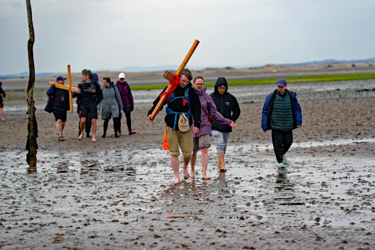 Pilgrims arrive at Holy Island carrying wooden crosses