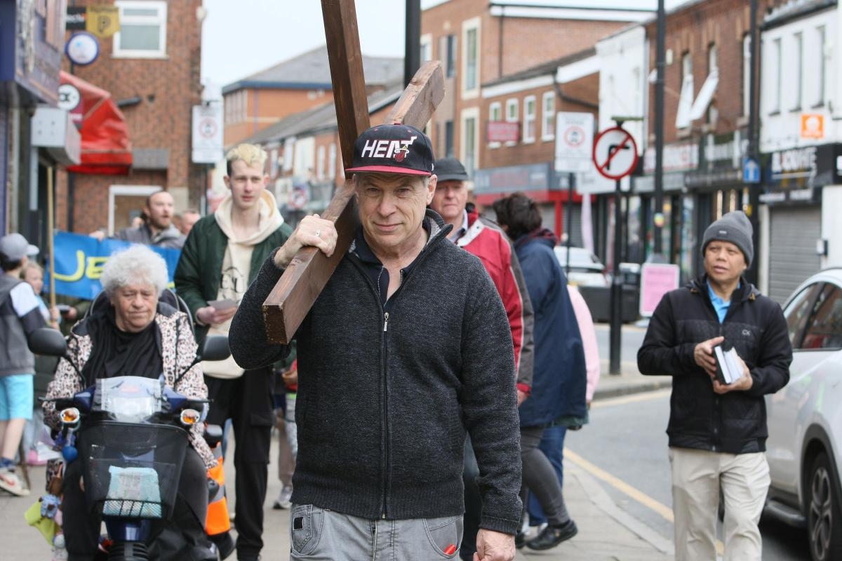 Church pastor and members march into town centre with cross for Good Friday