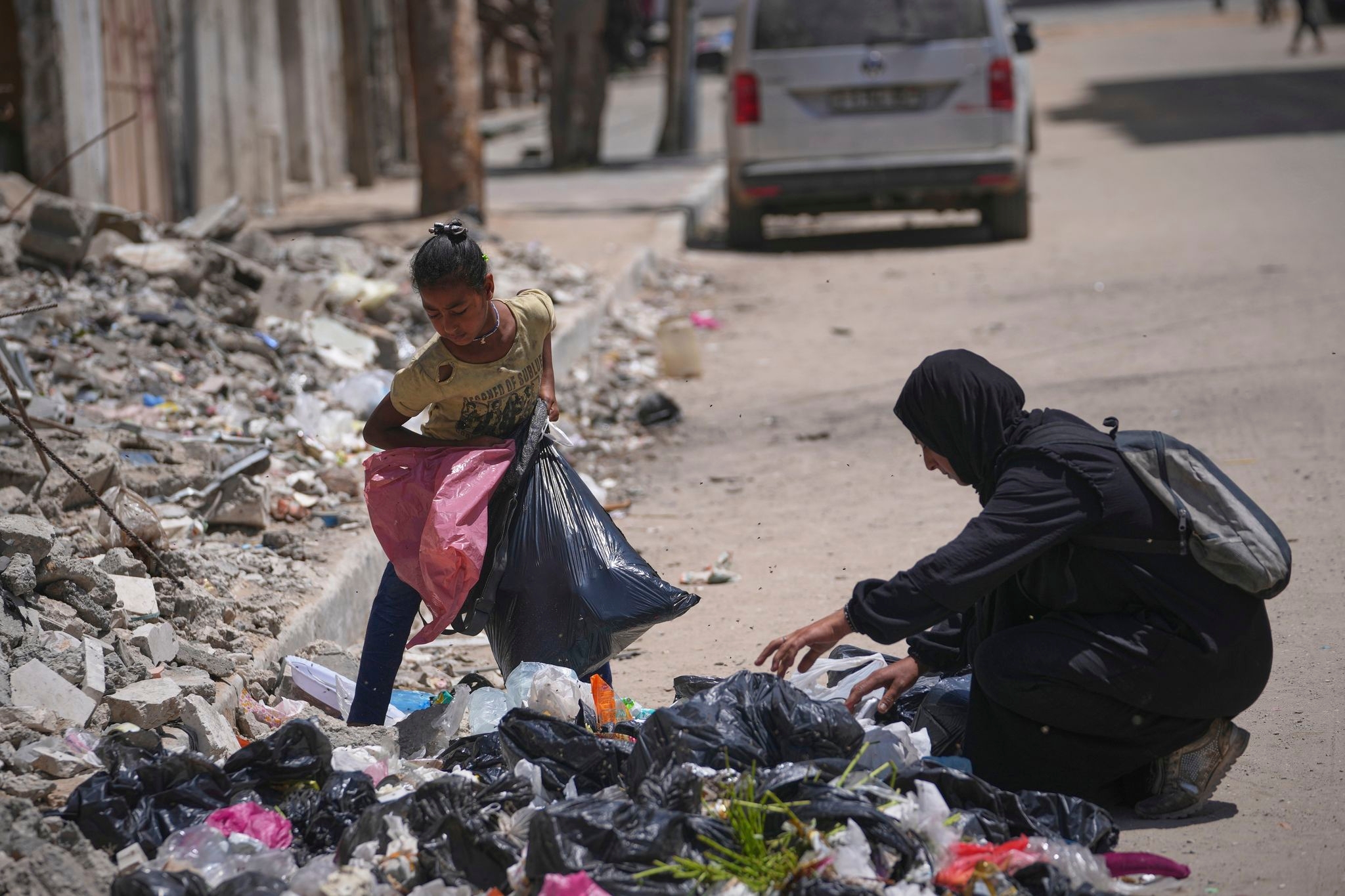 A family digs through trash for bits of food, showing Gaza's growing desperation