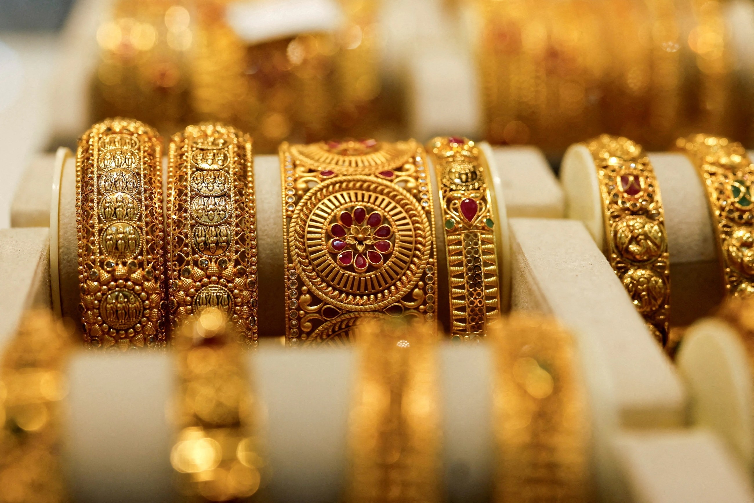 Gold rises on weaker dollar as investors eye developments