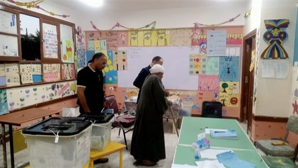 رئيس لجنة يساعد مسنا للإدلاء بصوته فى انتخابات الشيوخ بسوهاج (صور)